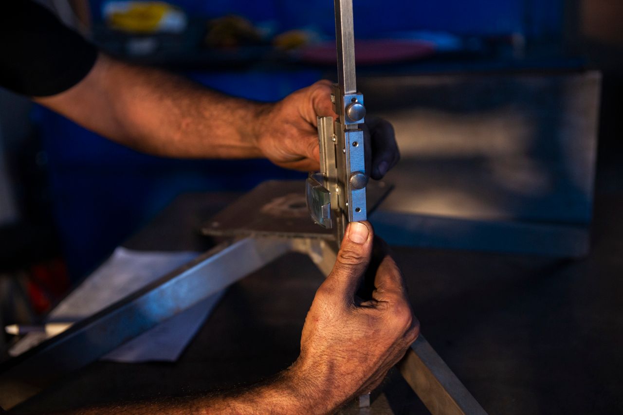 Close-up of hands focusing on precise metalwork using industrial tools in a workshop environment.