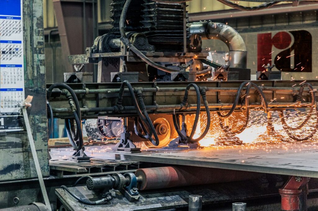 Detailed view of industrial machinery cutting metal, showcasing sparks and heat.